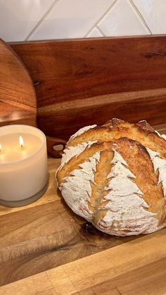 a loaf of bread sitting on top of a wooden table next to a candle