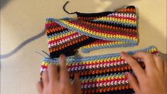 someone is crocheting the top part of a multicolored bag