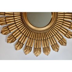 a gold sunburst shaped mirror on a white wall