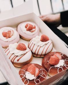 a box filled with donuts covered in icing and strawberries on top of each other