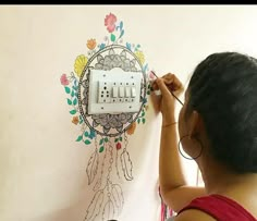 a woman is drawing on the wall with an electrical outlet