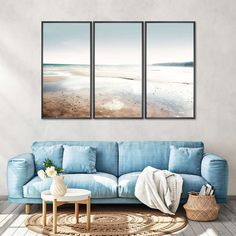 three paintings on the wall above a blue couch in a living room with a rug