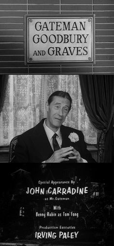 a man in a suit and tie sitting at a table with a sign above him