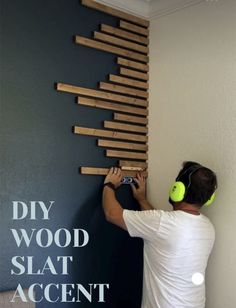 a man with headphones is placing wooden slats on the wall