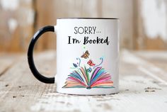 a black and white coffee mug with the words sorry i'm booked on it