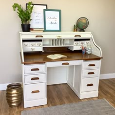 a white desk with drawers and a potted plant next to it on top of a hard wood floor