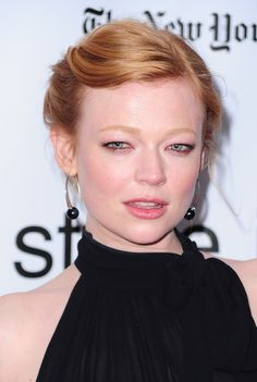 a close up of a person wearing a black dress with large hoop earrings on her head