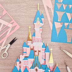 paper cut out of a castle with scissors and other crafting supplies on the table