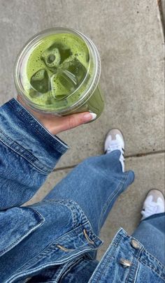 a person holding a drink in their left hand and wearing blue jeans on the other side