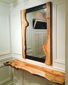 a wooden mirror frame sitting on top of a shelf next to a wall mounted mirror