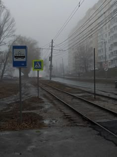 the train tracks are wet and there is no cars on them in the foggy weather