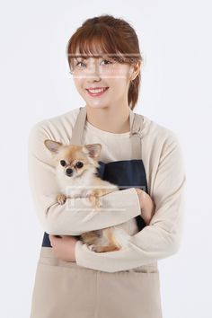 a woman in an apron holding a small dog with glasses on it's head