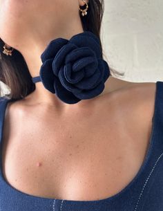 a close up of a person wearing a necklace with a flower on it