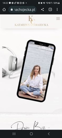 a cell phone with an image of a woman sitting on the ground next to headphones