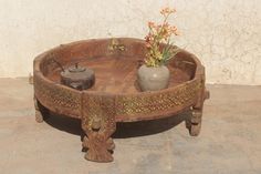 a wooden table with a potted plant on top and a vase in the middle