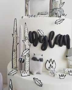 a white cake with black letters and decorations on the bottom layer is decorated in doodles