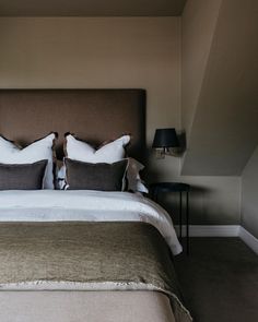 a bed with two pillows on top of it and a night stand next to it