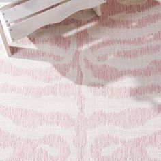 a white bench sitting on top of a pink rug