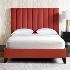 a bed with red headboard and white pillows in a bedroom next to a night stand