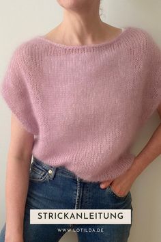 a woman wearing a pink sweater and jeans posing for the camera with her hands on her hips