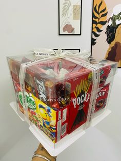 a bunch of sodas wrapped in plastic on top of a wooden table next to pictures