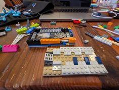 a laptop computer sitting on top of a wooden table covered in legos and other toys