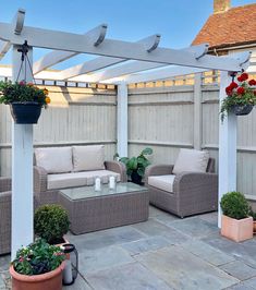 an outdoor living area with couches and potted plants