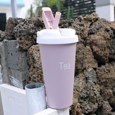 a pink coffee cup sitting on top of a wooden post