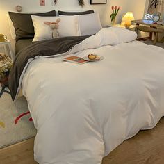 a bed with white sheets and pillows on top of it in a bedroom next to a desk