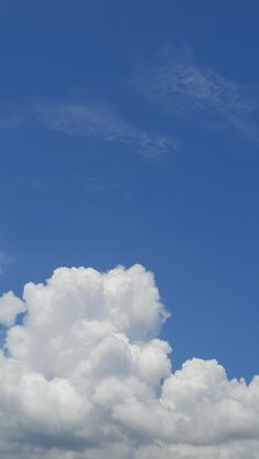 an airplane flying high in the sky on a sunny day with white clouds and blue skies