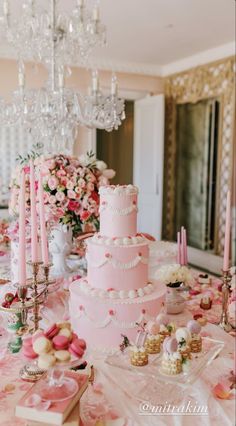 a pink cake sitting on top of a table covered in lots of flowers and candles