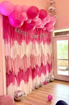 pink and white balloons are hanging on the wall