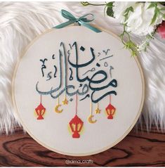 an embroidery pattern with arabic writing on it and flowers in the background, along with a white furnishing