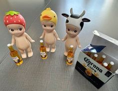 three little figurines are standing next to bottles of beer and an open box