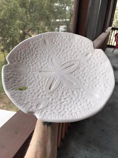 a white plate sitting on top of a window sill next to a person's hand