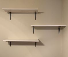 three white shelves are hanging on the wall