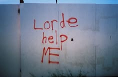 graffiti written on the side of a building that says lorde help me with red spray paint