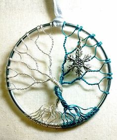 a wire tree ornament hanging on a white wall next to a blue string