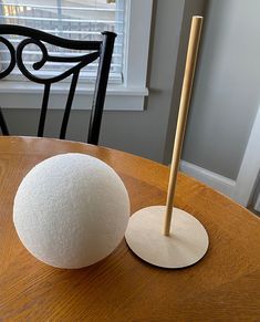 a wooden table with a white ball on it and a stick sticking out of the top