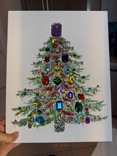 a hand holding up a card with a christmas tree made out of jeweled objects