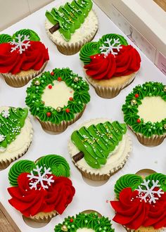 twelve decorated christmas cupcakes sitting in a box on a table with white and green frosting