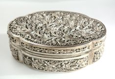 an ornate silver box sitting on top of a white tableclothed surface with filigrees in the middle