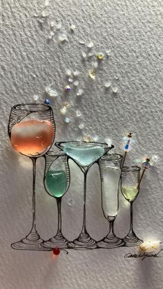 four wine glasses filled with different colored liquid and confetti sprinkles