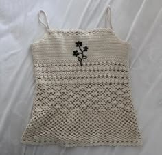 a white crocheted bag with a black flower on it