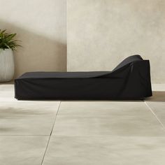 a black couch sitting on top of a tiled floor next to a potted plant