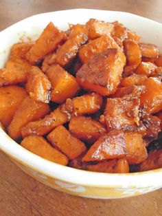 a white bowl filled with cooked carrots on top of a wooden table