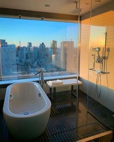 a bath tub sitting next to a window in a bathroom with a view of the city