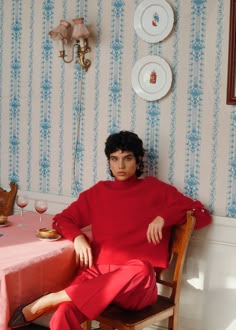 a woman sitting at a table in a red outfit