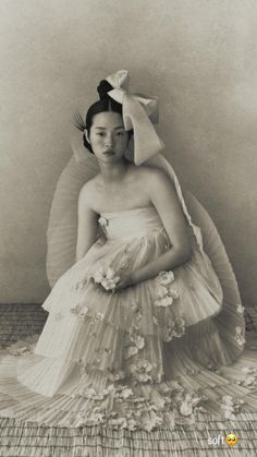 an old photo of a woman in a dress with flowers on the skirt and headband