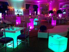 a room filled with tables and chairs covered in purple lighting at the end of it